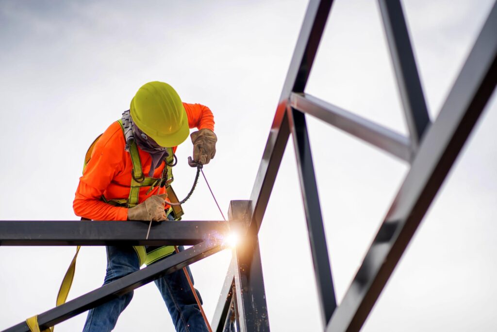 a technician in protective gear working on assembling a structure with the sun in the background