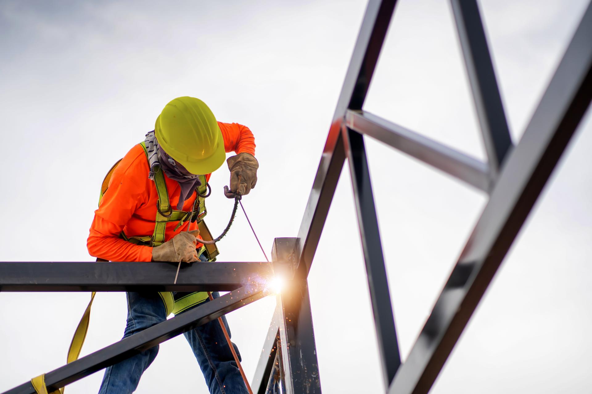 a technician in protective gear working on assembling a structure with the sun in the background